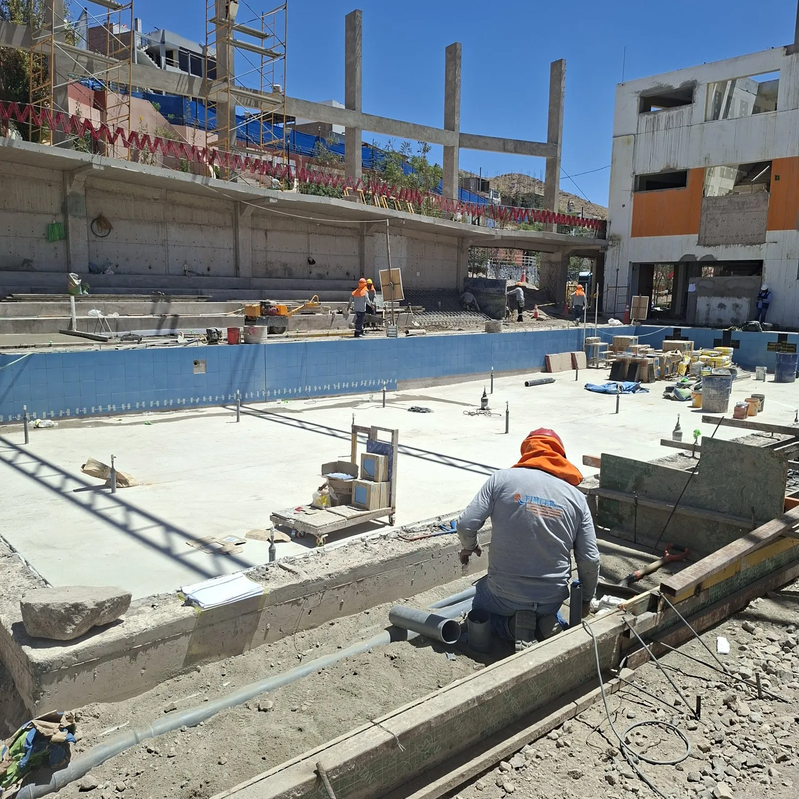 Técnico de FIMCER instalando tuberías de PVC junto al vaso de una piscina en construcción, con las paredes enchapadas en azul