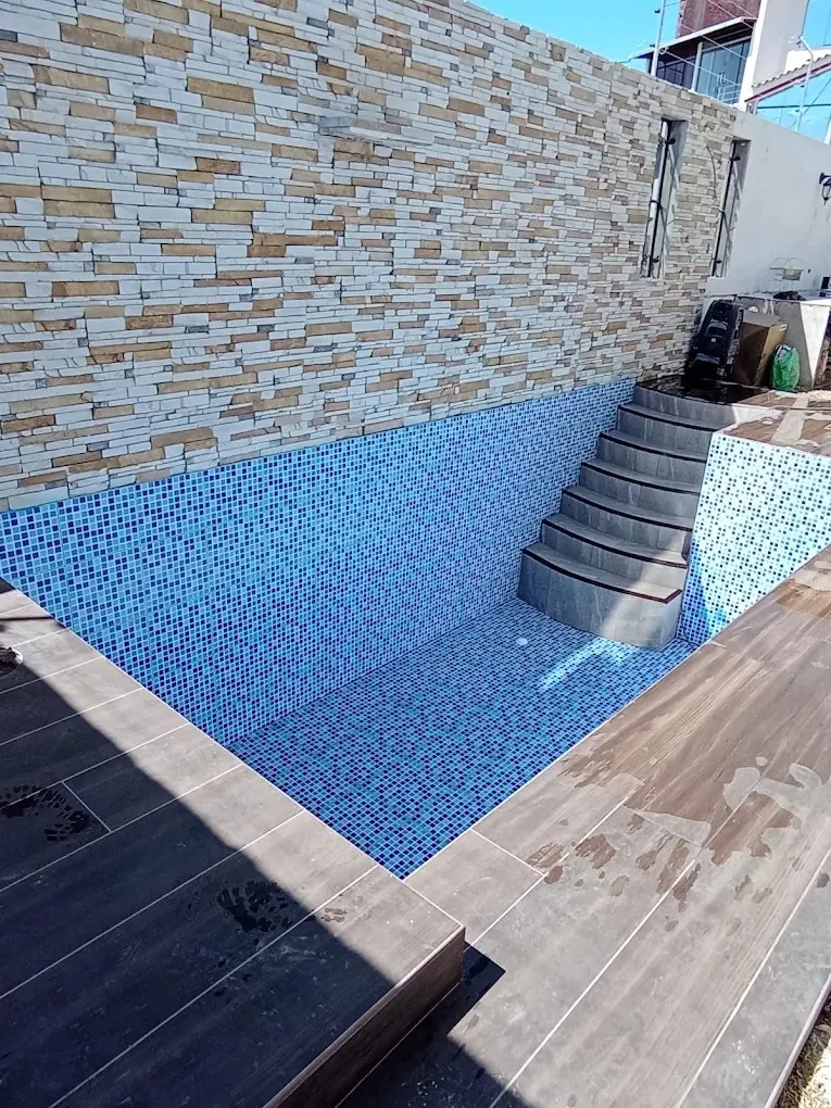 Piscina residencial vacía recién enchapada con venecitas azules y escalera de ingreso