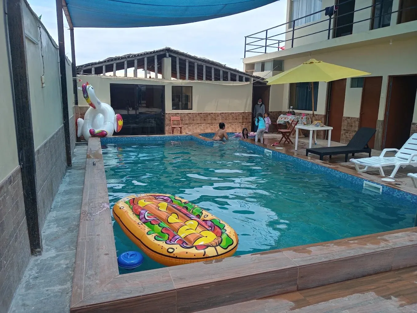 Piscina residencial terminada con enchape de venecitas, borde de madera y área de descanso